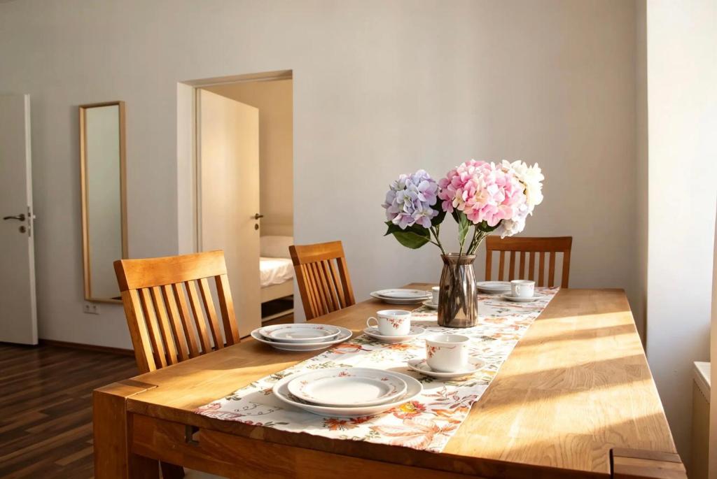 a dining room table with a vase of flowers on it at Heritage Courtyard Apartment in Bruck an der Leitha