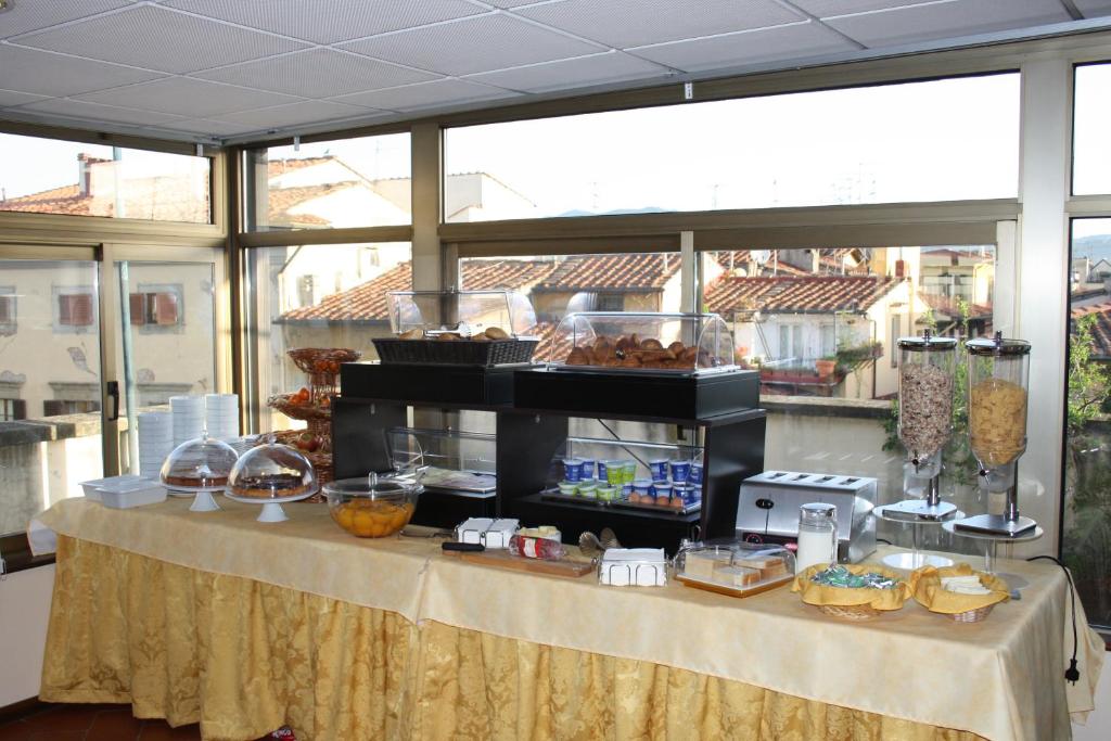 una mesa con comida en ella en una habitación con ventanas en Hotel Bodoni, en Florencia