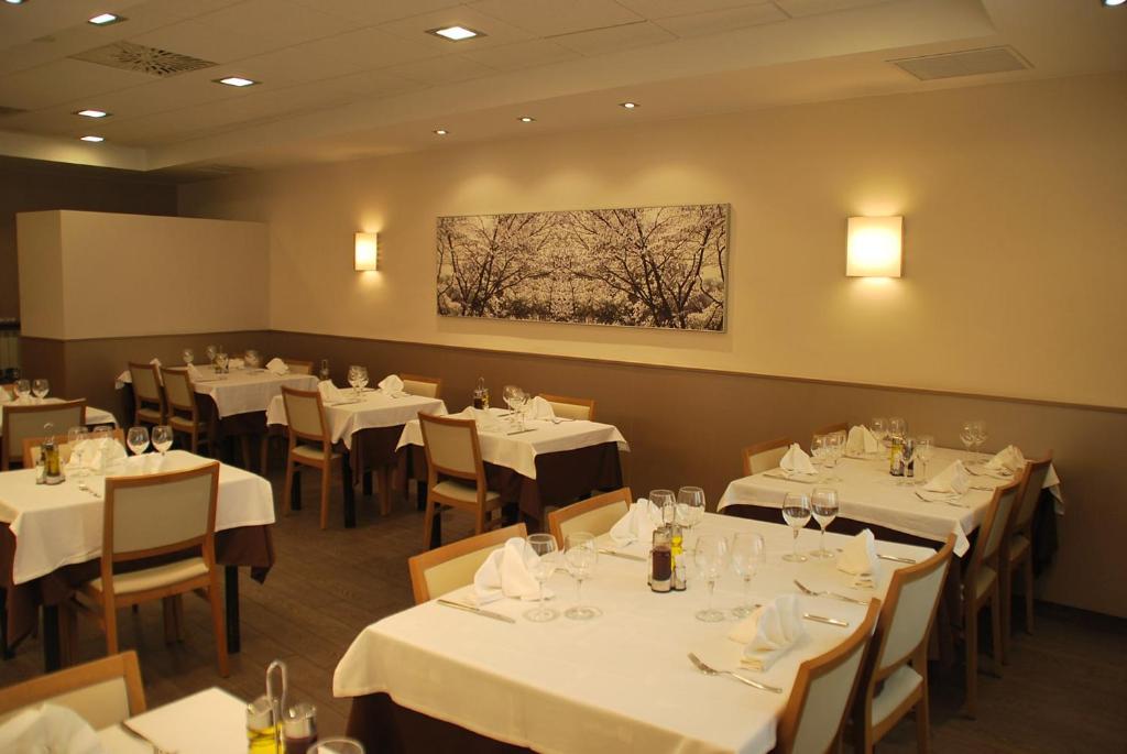 a restaurant with white tables and chairs and a painting on the wall at Aparthotel Meseguer in Alcañiz