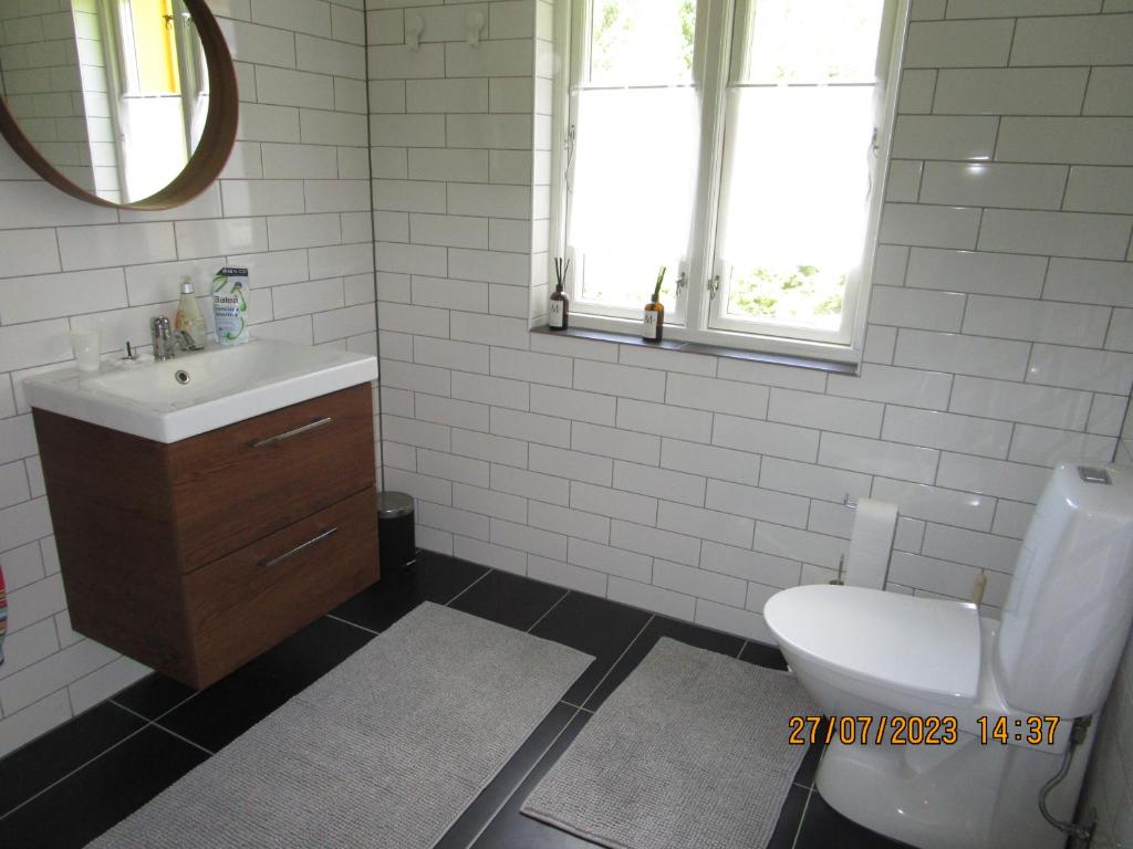 a bathroom with a sink and a toilet and a mirror at Mysig huset in Strömsnäsbruk
