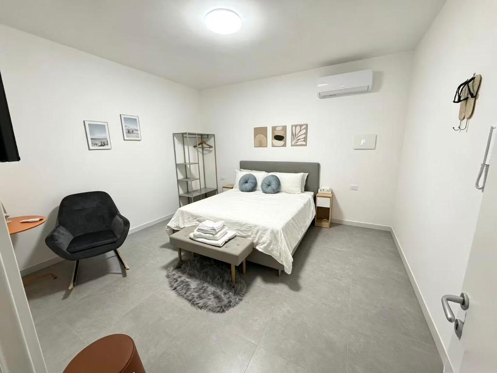 a white bedroom with a bed and a chair at Casa sissy in Chioggia