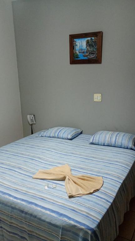 a bed with a towel sitting on top of it at Primeiro Hotel in Ilha Solteira