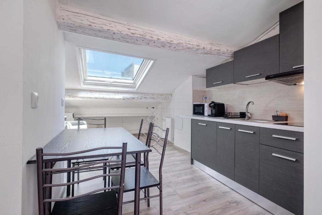 a kitchen with black cabinets and a table with chairs at Studio Centre Cannes, Rue d’Antibes in Cannes
