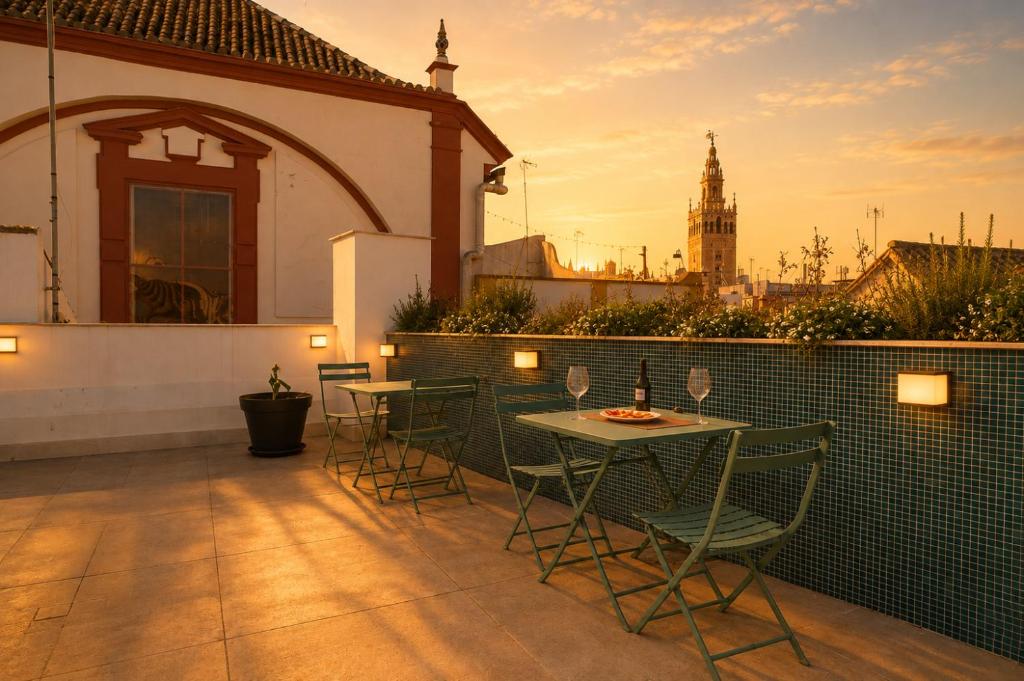 a patio with four chairs and a table with wine glasses at Posada de los Venerables in Seville