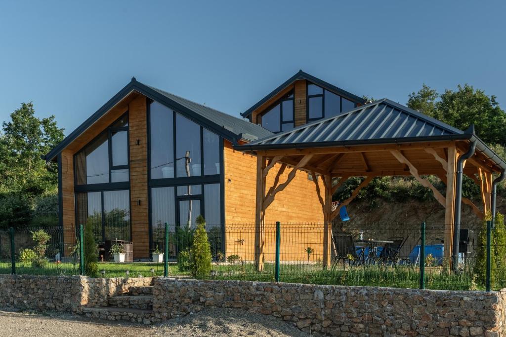 a house with a black roof and a stone wall at Golden view Villa in Prishtinë