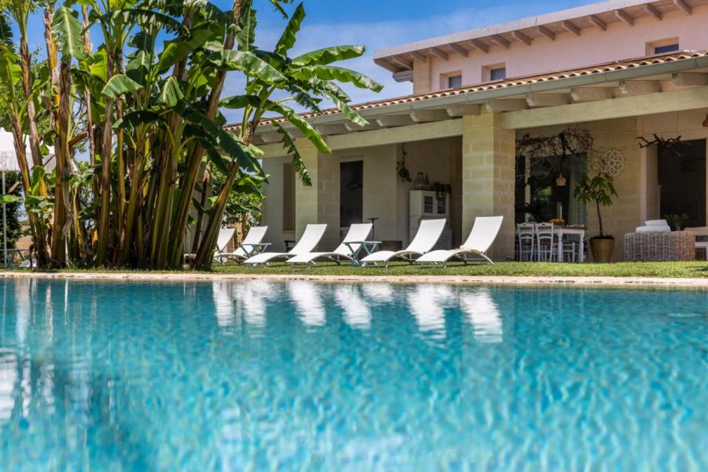 a swimming pool with lounge chairs in front of a house at Villa Reginella - Rive del Salento in Lecce