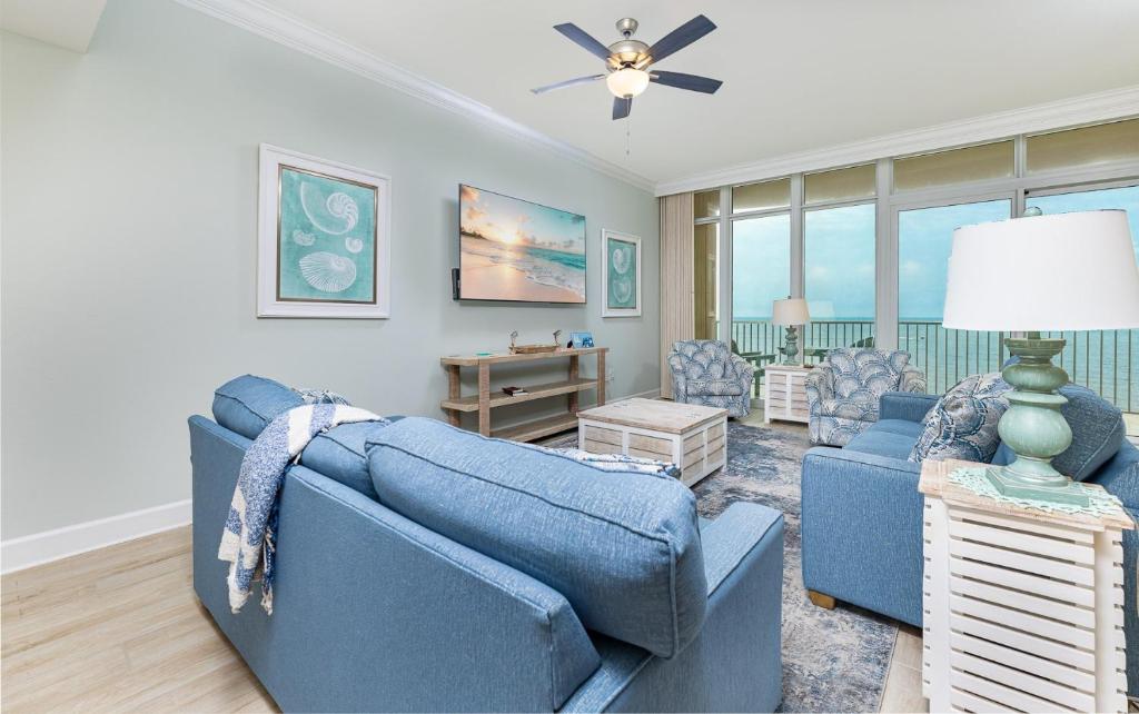 a living room with a blue couch and chairs at Phoenix Gulf Towers 706 condo in Gulf Shores
