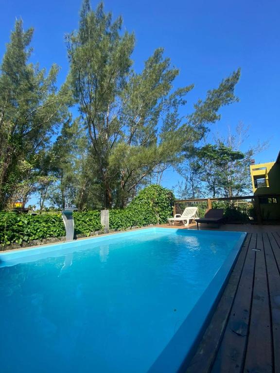 a swimming pool with blue water and trees at Hotel Pousada Capão in Garopaba