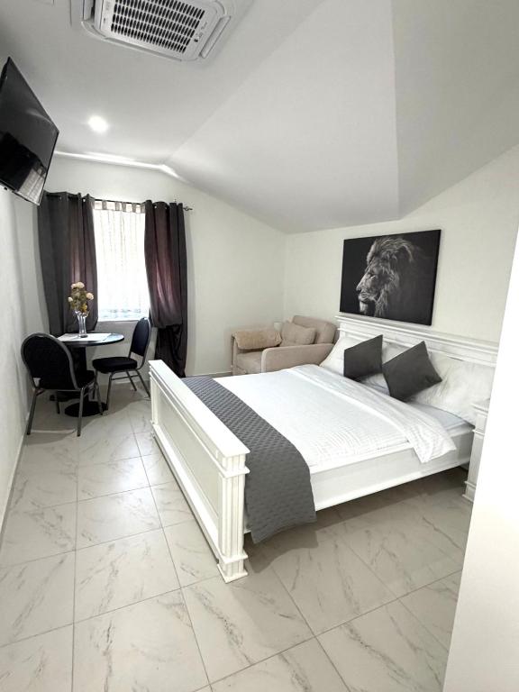 a bedroom with a large white bed and a table at Herz Apartmani in Igalo