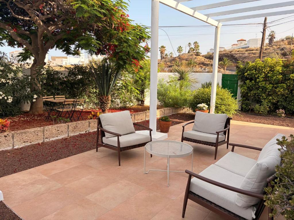 a patio with three chairs and a glass table at The Hidalga's cozy house in Arafo