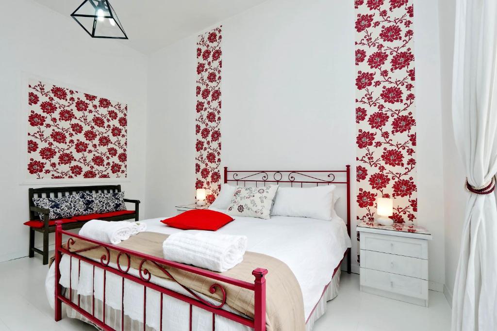 1 dormitorio con 1 cama con papel pintado de flores rojas en Charming Apartment Antonia 300 mt from Colosseum, en Roma