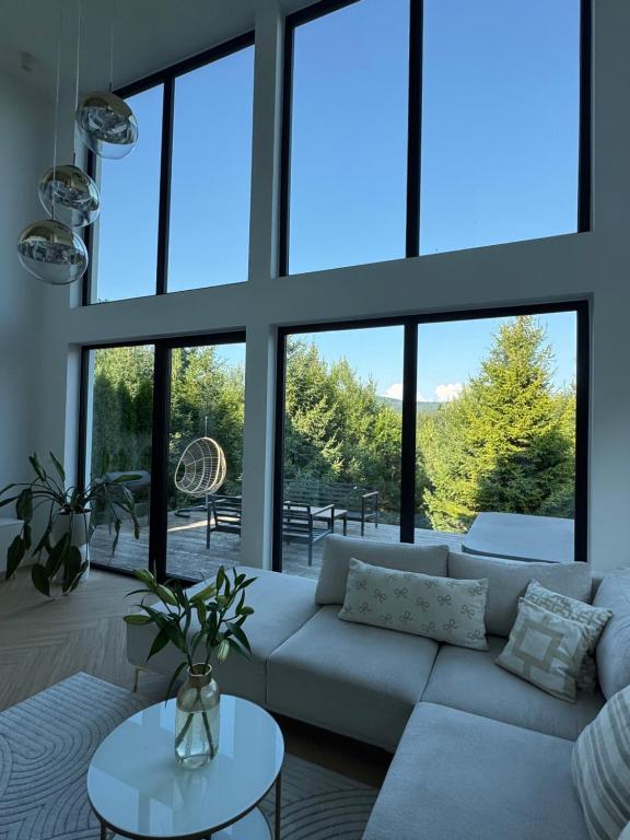 a living room with a white couch and large windows at Black Diamonds Hill in Istebna