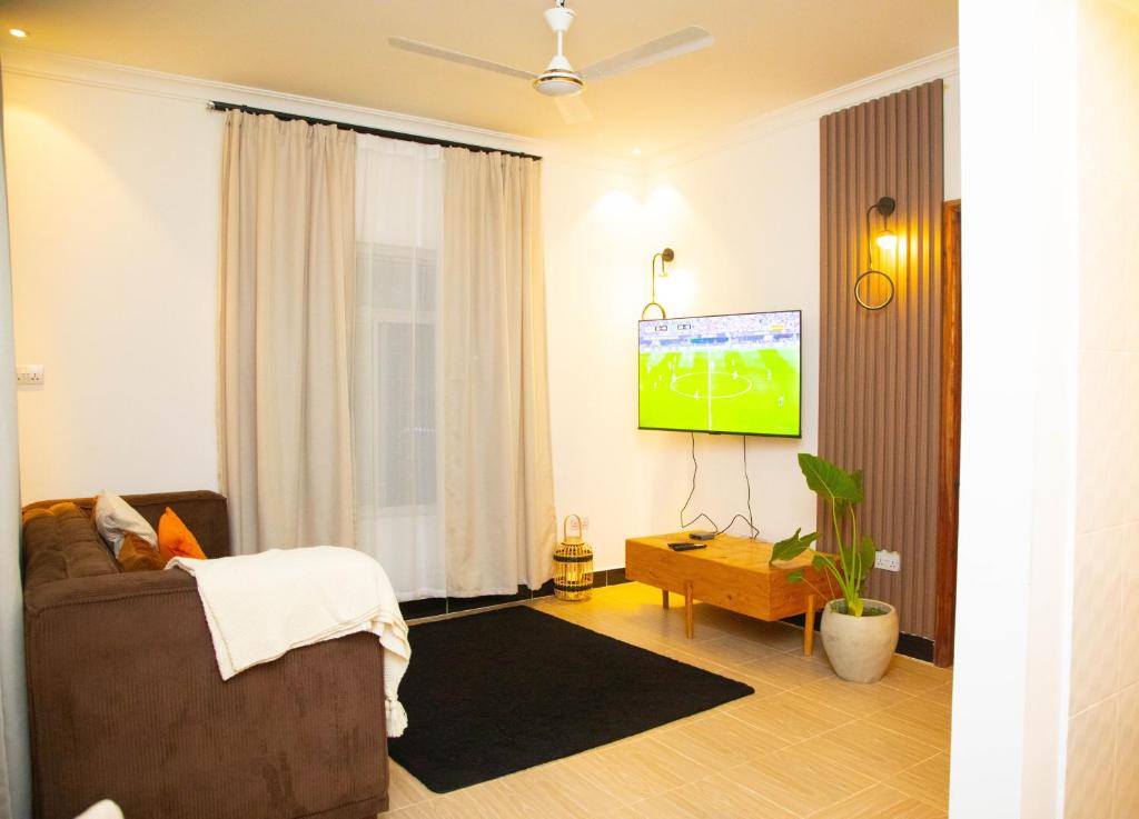 a living room with a couch and a flat screen tv at Boha Zanzibar Beach House in Bwejuu