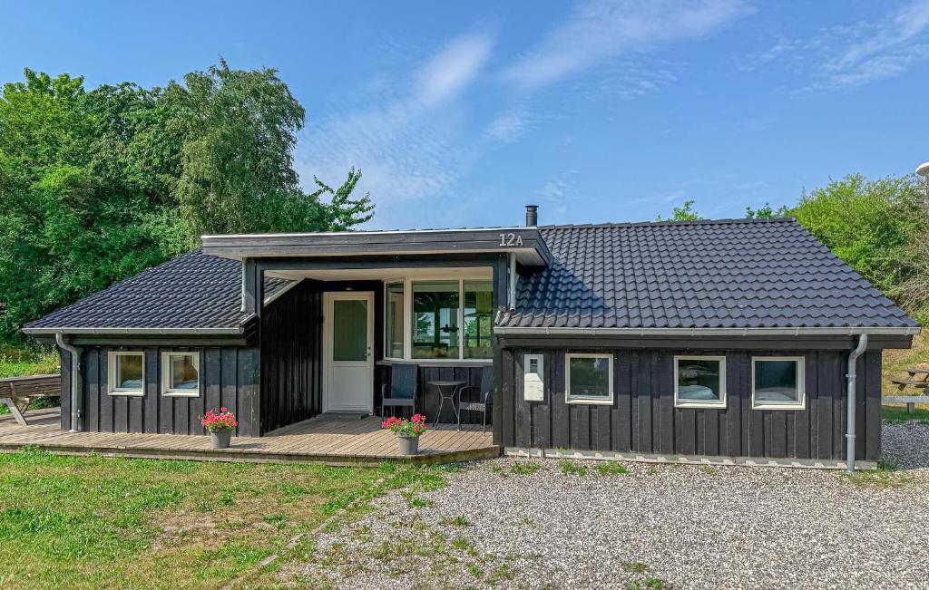 a small black house with a deck at Lovely Home In Ebeltoft With Sauna in Ebeltoft