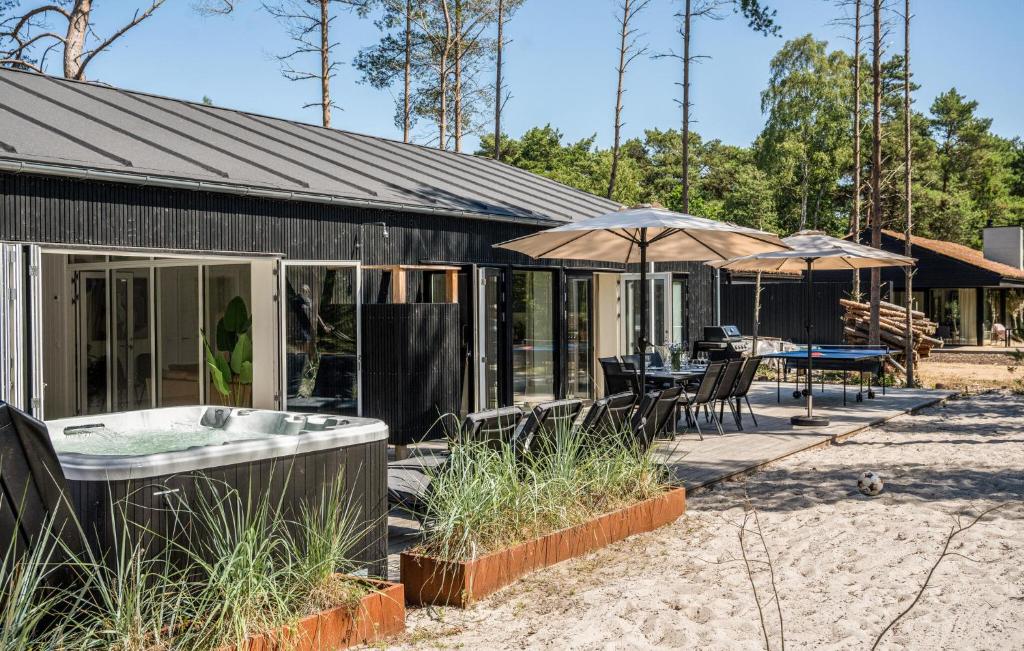 a house with a tub and a table and umbrella at Nice Home In Nexø With Sauna in Neksø