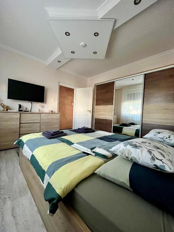 a large bedroom with two beds and a tv at Maros Apartman in Makó