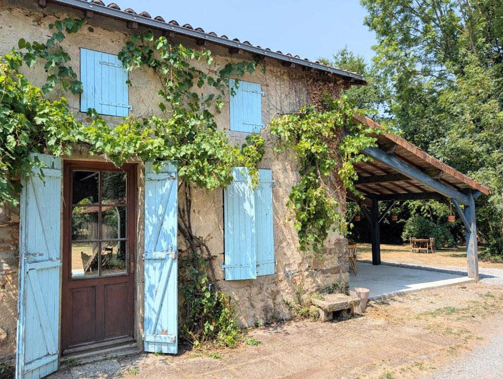 an old building with blue shutters and a door at Clos de Beauregard in Cirière
