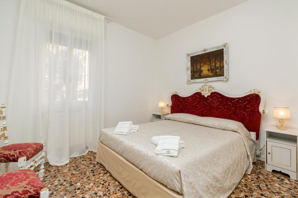 um quarto com uma cama grande e uma cabeceira vermelha em Venice Apartments San Samuele em Veneza