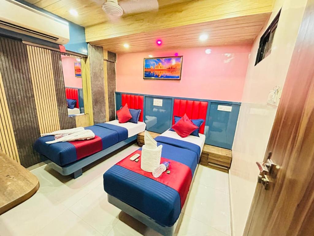 a room with three beds with red and blue pillows at Hotel al raihan in Mumbai