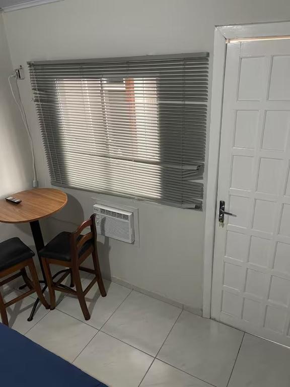 a room with a table and a chair and a door at Pousada Coral in Osório