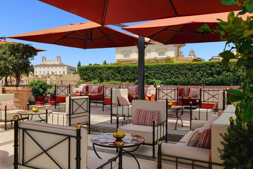 a patio with tables and chairs and umbrellas at Hotel d’Inghilterra Roma – Starhotels Collezione in Rome
