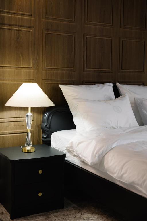 a bed with white sheets and a lamp on a night stand at Lumen in Kostanay