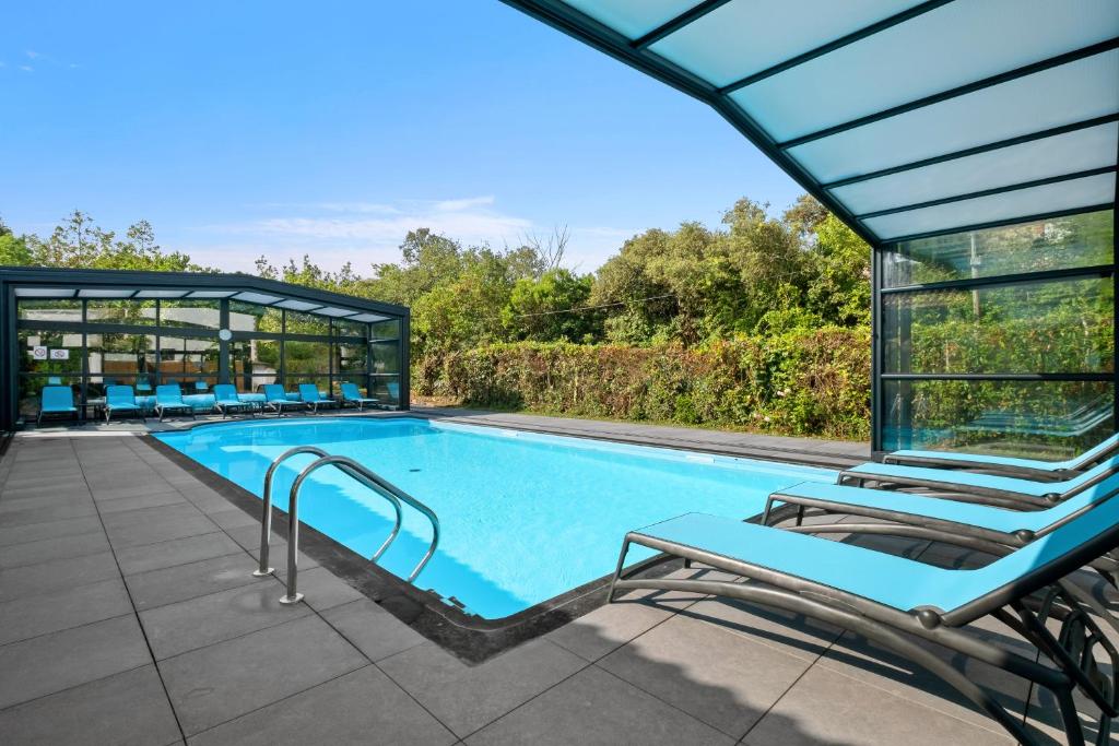 a swimming pool with lounge chairs next to a building at Hotel Saint Paul in Noirmoutier-en-l'lle