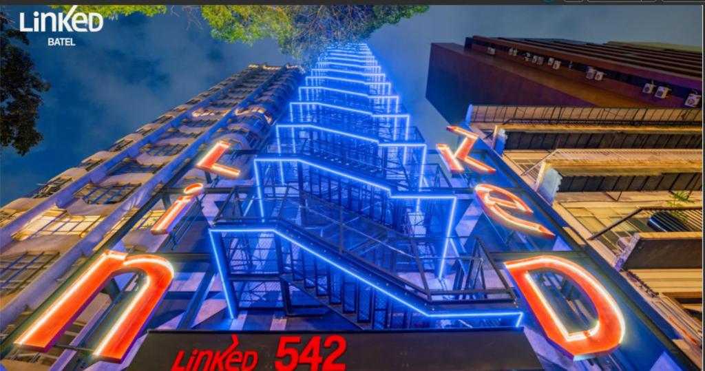 a building with neon signs on the side of it at Linked Batel Curitiba by Xtay in Curitiba