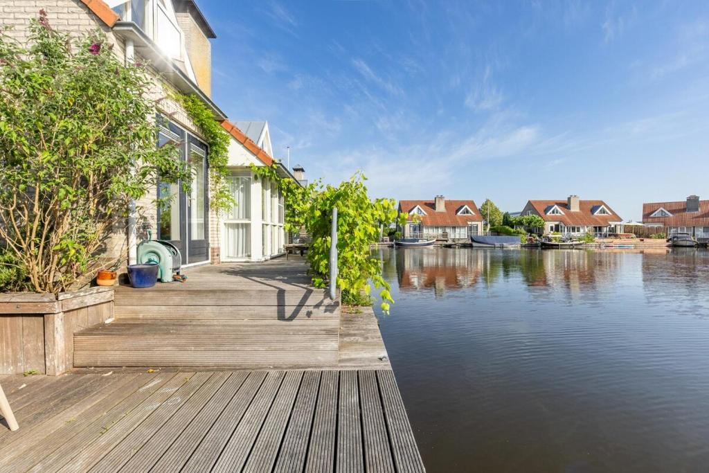 a house with a dock next to a body of water at Cozy Waterfront Getaway for a Perfect Holiday in Langweer
