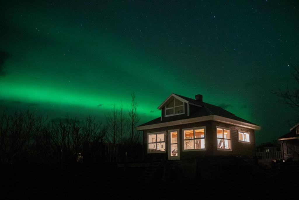 a house with the green northern lights in the sky at Solhaven in Selfoss