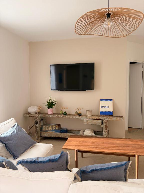 a living room with two couches and a flat screen tv at Maison de la plage - Dossen Santec - Réservations à la semaine, de week-ends en week-ends in Santec