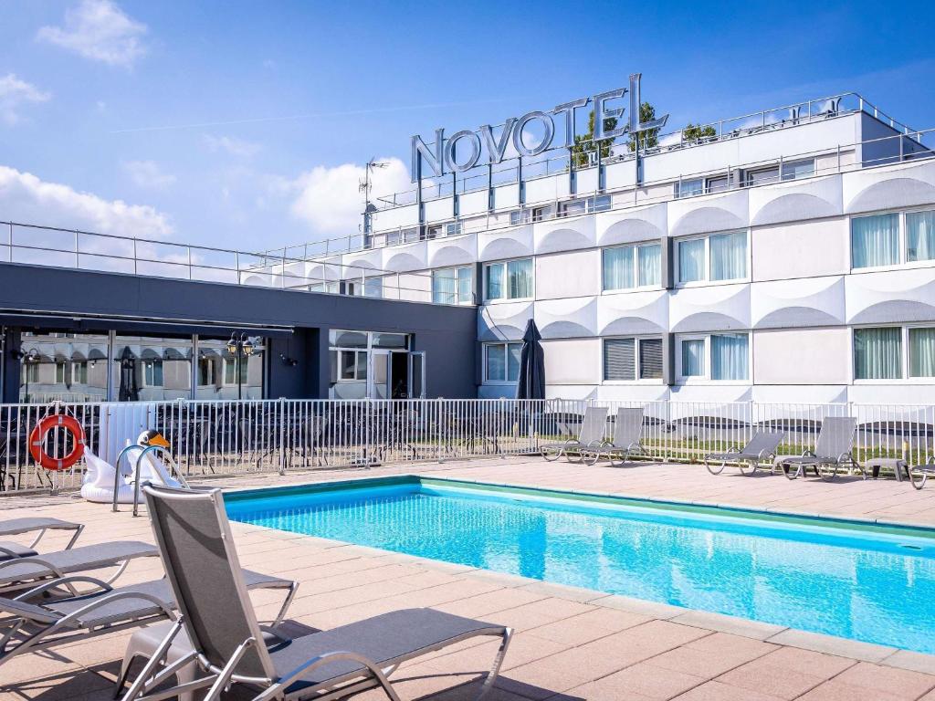 a hotel with a swimming pool in front of a building at Novotel Mulhouse Bâle Fribourg in Sausheim
