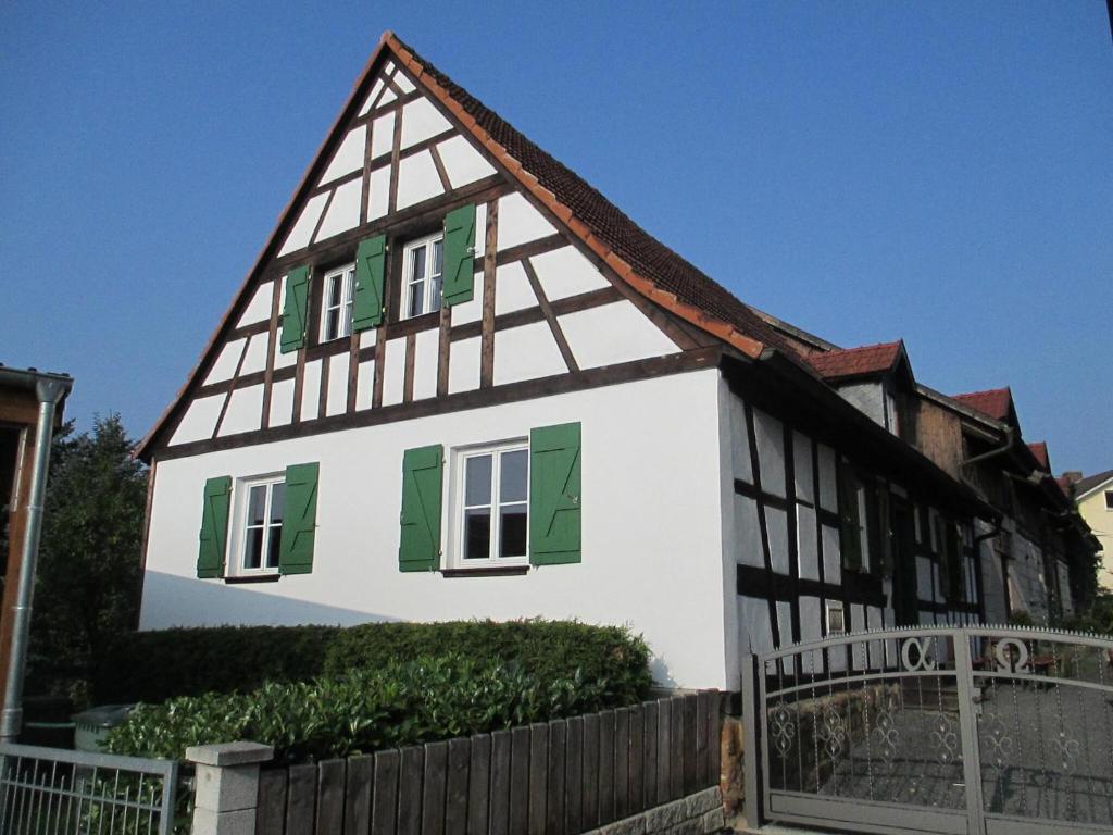 a house with green shuttered windows and a fence at Schlossgut Franken in Redwitz an der Rodach