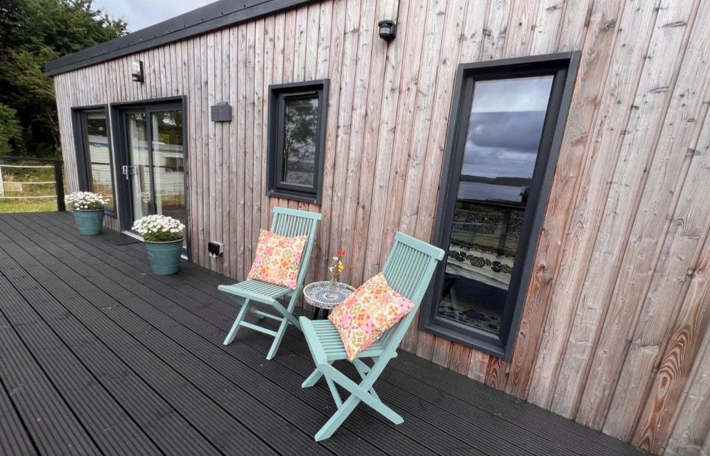 two chairs and a table on a wooden deck at Tiny Mara in Uig