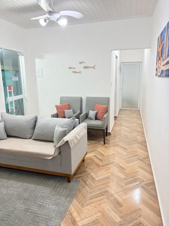 a living room with two couches and wooden floors at Casa centro de Peruíbe in Peruíbe