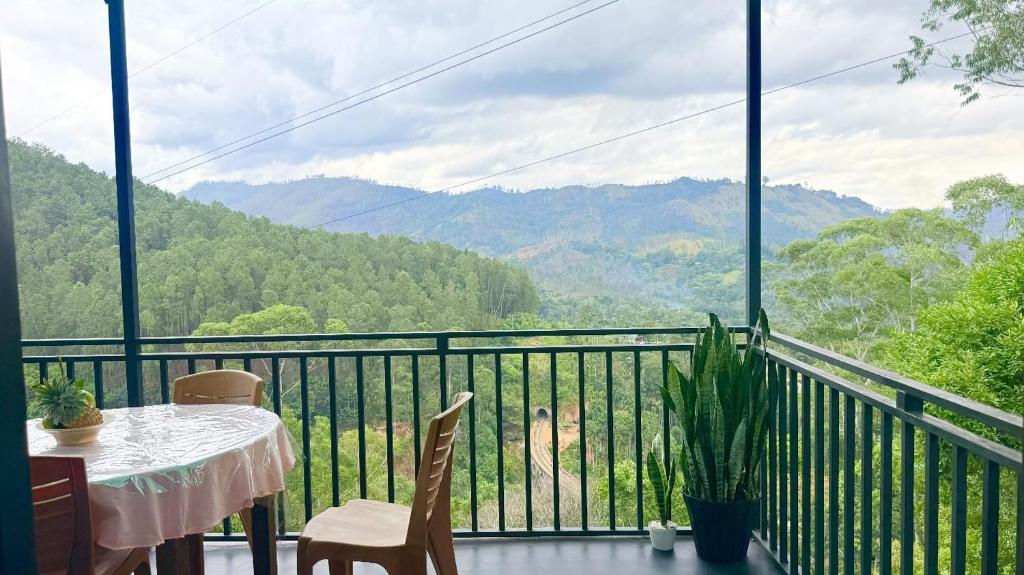 a table and chairs on a balcony with a view at Blooming Hill Cabin Ella in Ella
