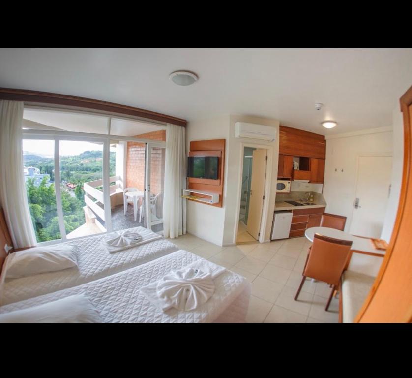 a bedroom with a bed and a kitchen with a window at Apartamento nas Termas no Apart-hotel in Gravatal