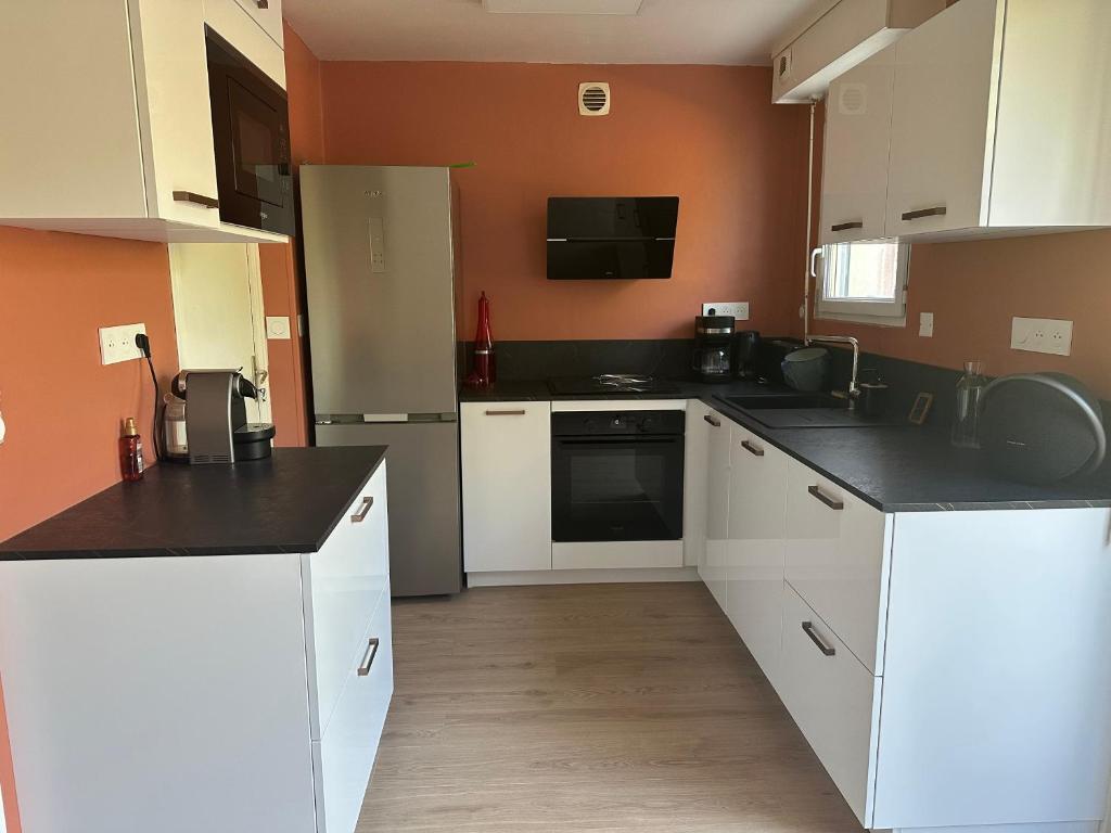 a kitchen with white cabinets and black counter tops at Maison de Corinne in Sarzeau