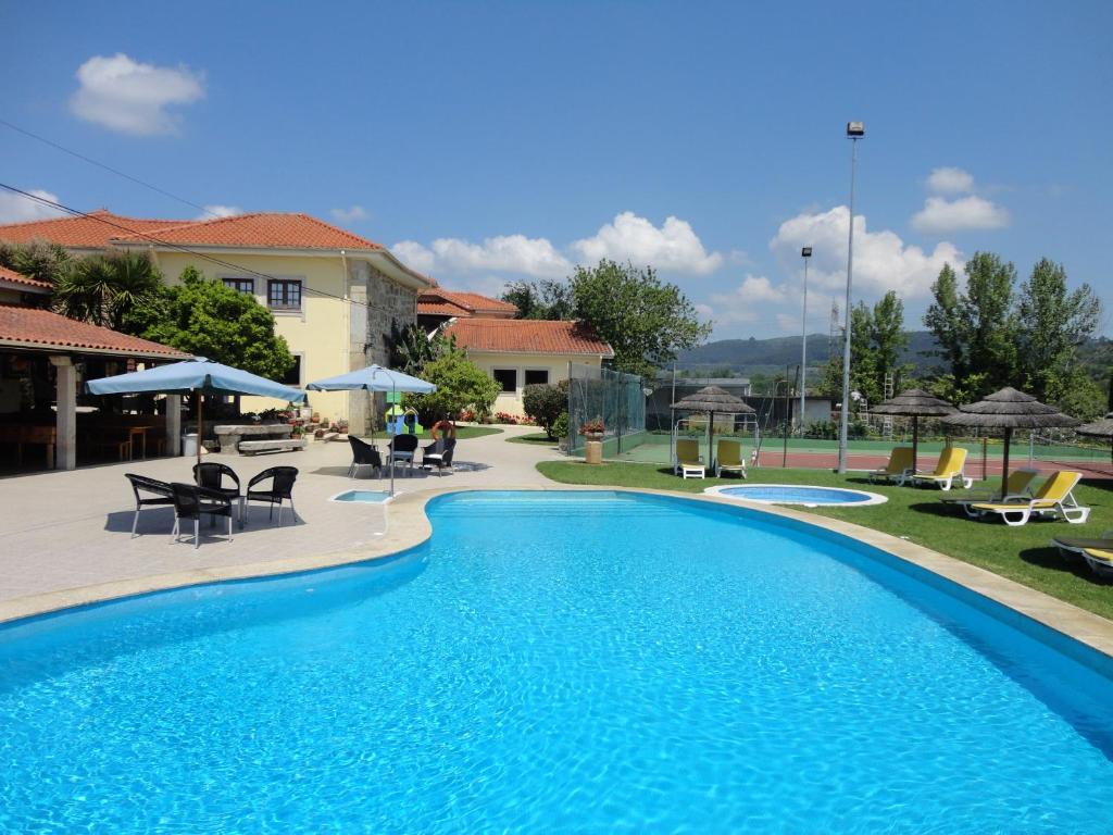 a swimming pool with chairs and umbrellas next to a house at Agroturismo Quinta Dom José in Vila Verde