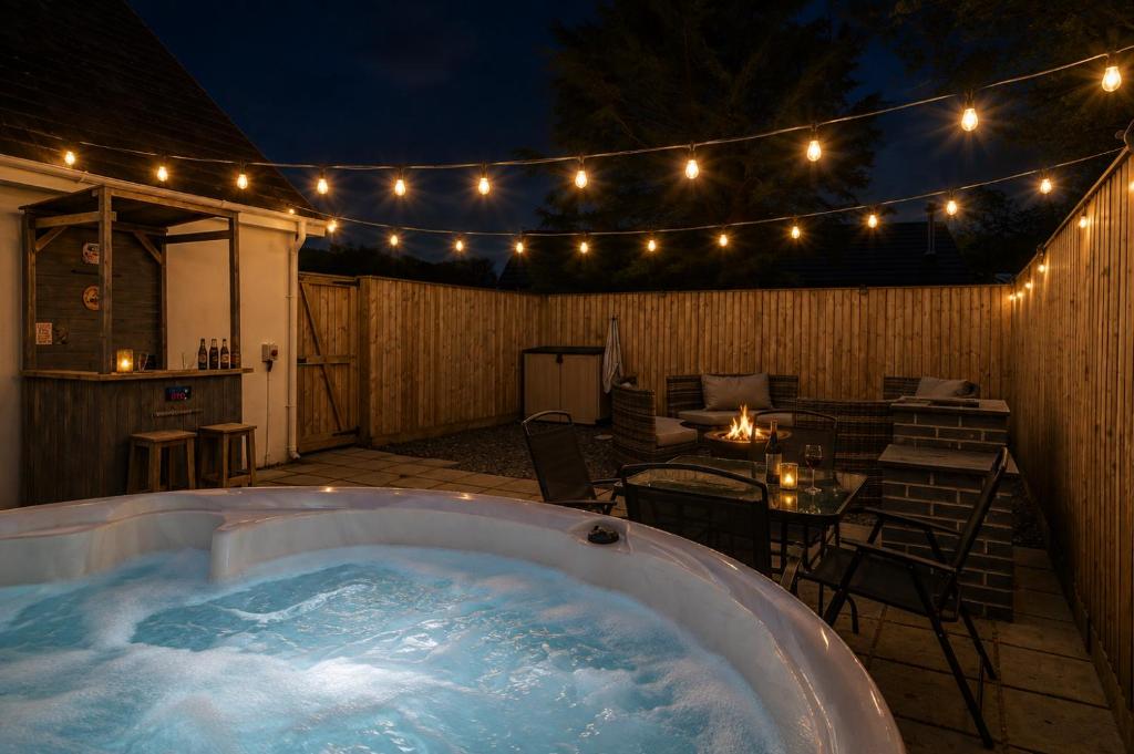 a hot tub on a patio with a table and lights at Hazel Cottage in Tenby
