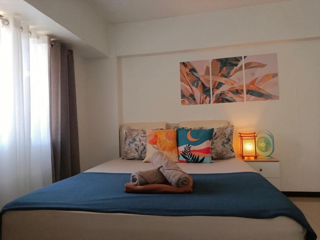 a bedroom with a bed with a blue blanket at Affordable Travellers Studio Condo near Mactan Airport by A&C in Pusok