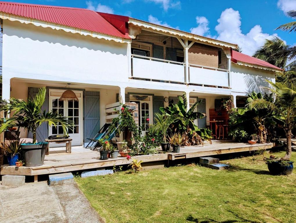 a house with a wooden deck and plants in the yard at Sur L'Anse in Terre-de-Haut