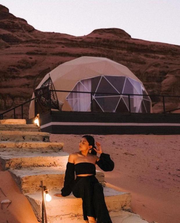 a woman sitting on steps in front of a tent at Luxury cMp in Al Karāmah
