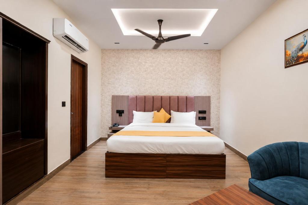 a bedroom with a large bed and a blue chair at Hotel Emience in Chandīgarh