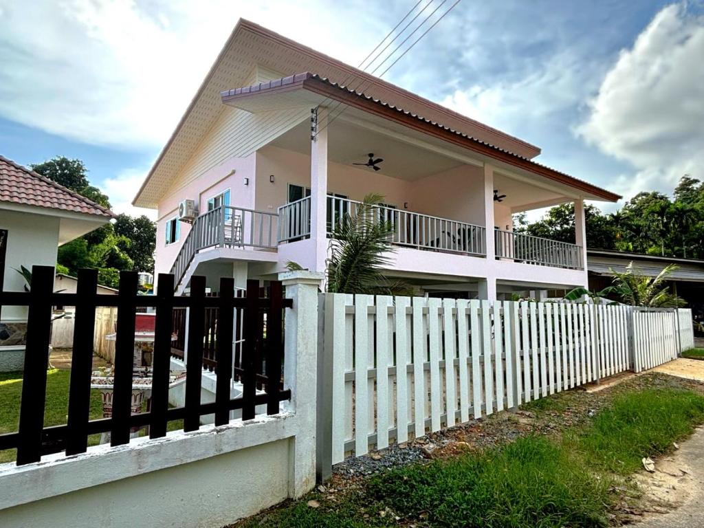 a house with a white picket fence at Duplex villa in Khlaung Phai Bae