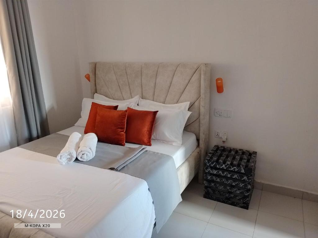 a bedroom with two beds with orange and white pillows at Chemba's Paradise in Galu
