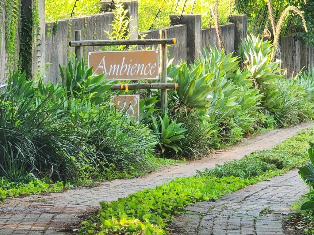 a sign in a garden next to a path at Ambience Inn White River in White River