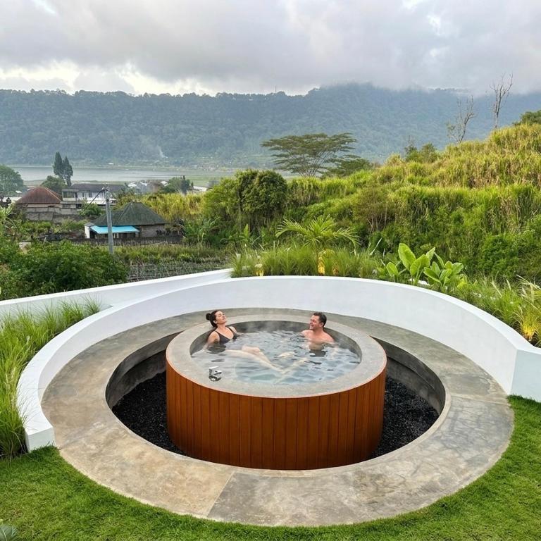 two people in a hot tub in the grass at DELIMA A Frame House in Singaraja