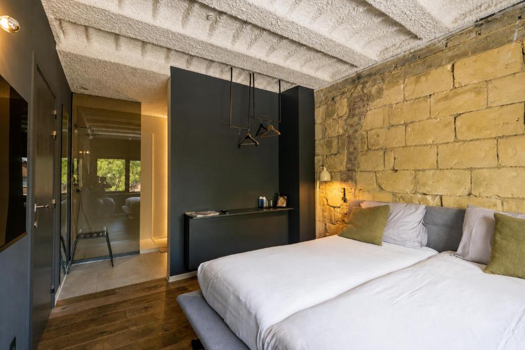 a bedroom with a white bed and a brick wall at K-Kanne in Kanne