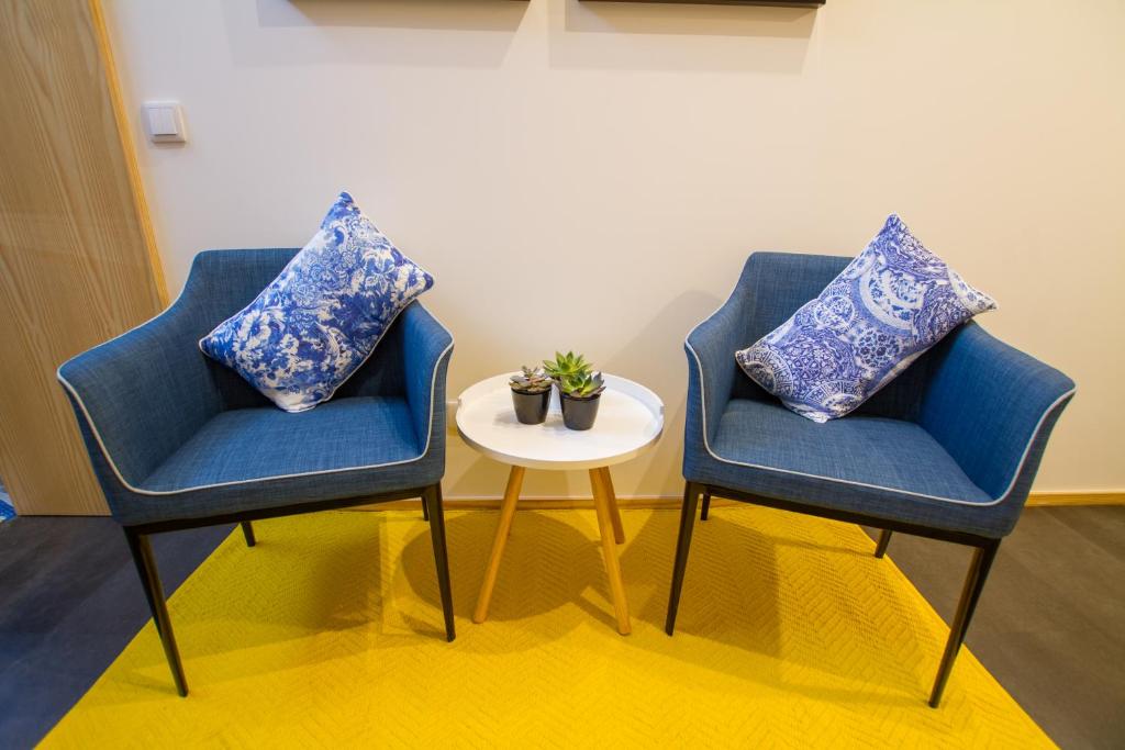duas cadeiras azuis sentadas ao lado de uma mesa com almofadas em Casa dos Mercanteis em Aveiro